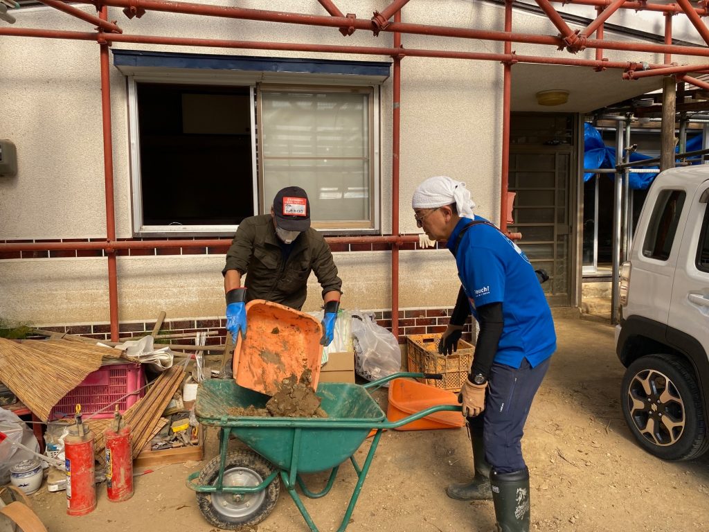 床下に入り込んだ泥を窓から出し運ぶ様子